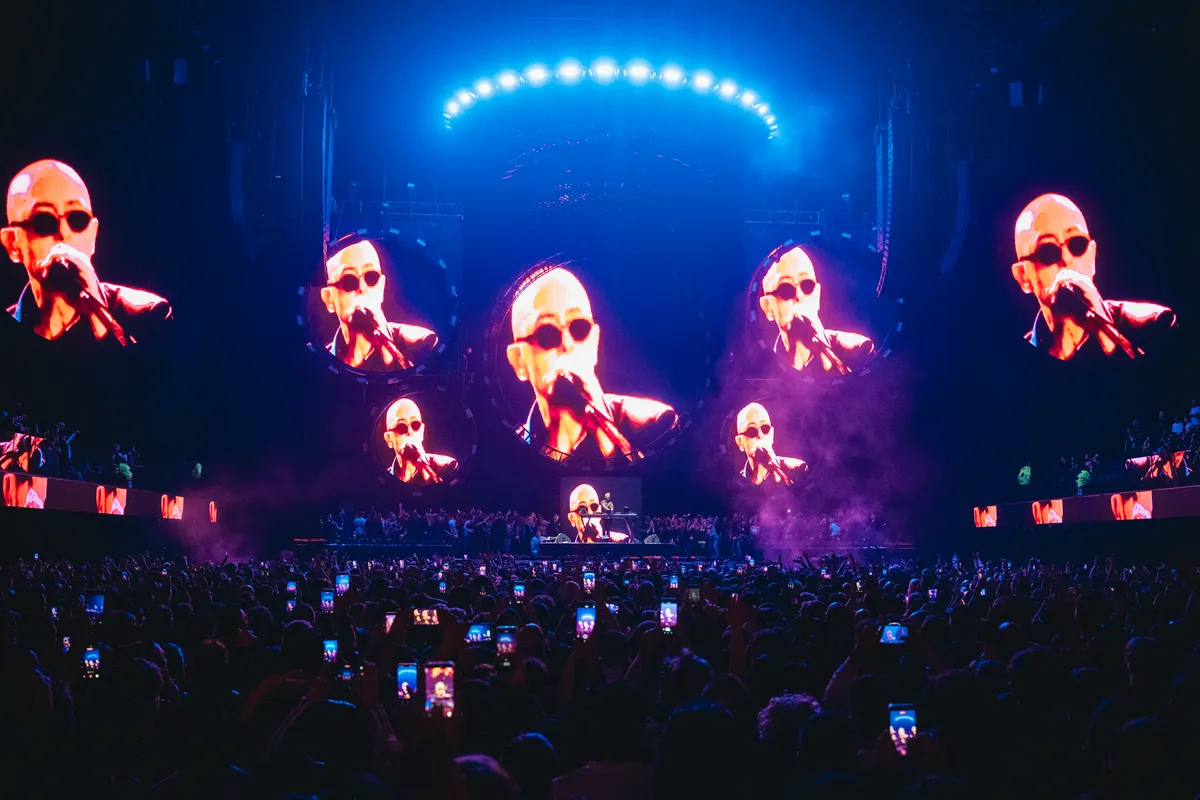 Las pantallas circulares del Movistar Arena muestran al Indio Solari cantando con anteojos oscuros, mientras el público graba con sus teléfonos