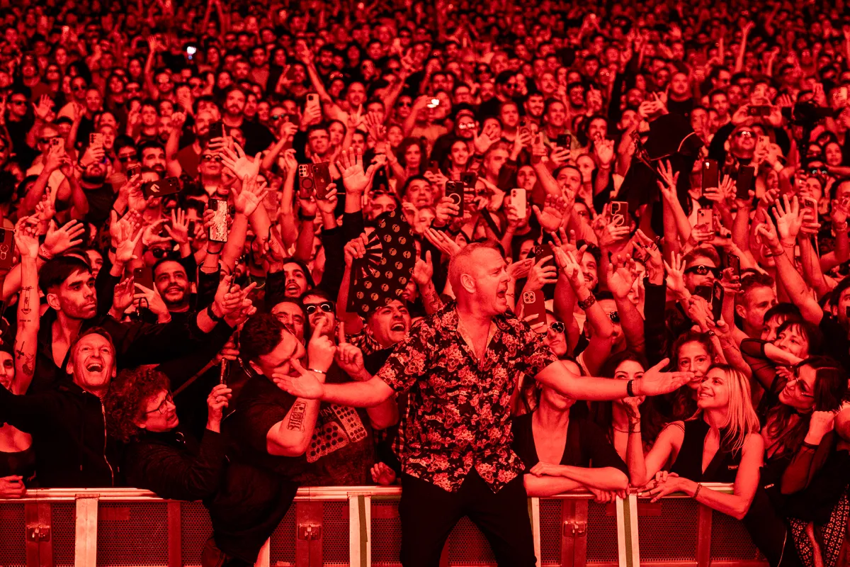 Norman Cook contra la valla del Movistar Arena, entre el público iluminado de rojo, con decenas de manos y teléfonos alrededor